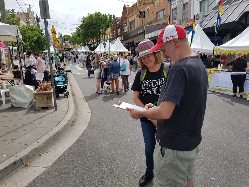 Two volunteers with a clipboard at a street festival stall