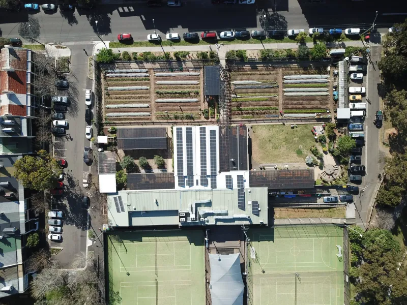 Overhead view of Camperdown Commons with solar panels on the roofs beside garden beds and courts