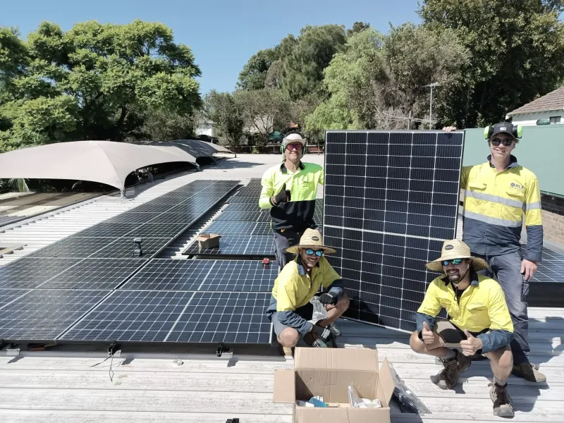 Four installers in hi-vis on a roof with solar panels