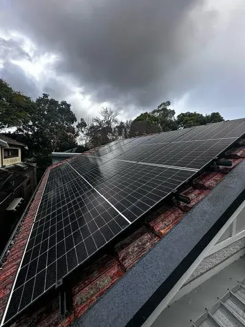 New solar panels on a tiled roof under a stormy sky