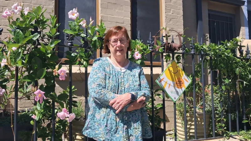 Lindsay standing beside the front fence of her Leichhardt home