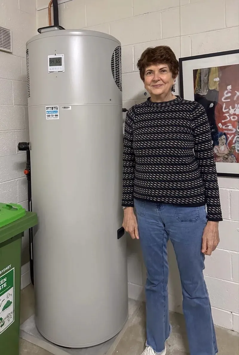 Lucie standing beside her new heat pump hot water tank