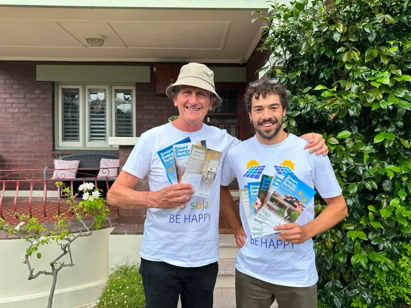 Two volunteers in Go Solar T-shirts holding Smart Energy Switch guides
